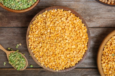 Bowls and spoon with dried peas on wooden background, top view