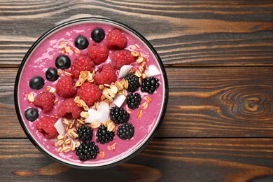 Photo of Delicious acai smoothie with berries and oatmeal on wooden table, top view. Space for text