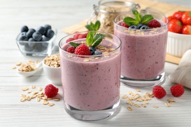Photo of Tasty smoothie with berries, mint and oatmeal on white wooden table
