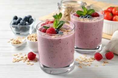 Tasty smoothie with berries, mint and oatmeal on white wooden table