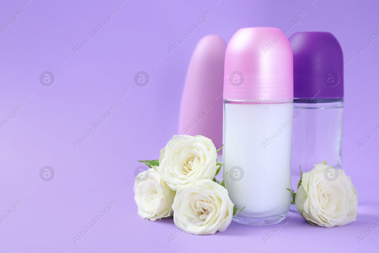 Photo of Composition with different female roll-on deodorants on purple background, space for text