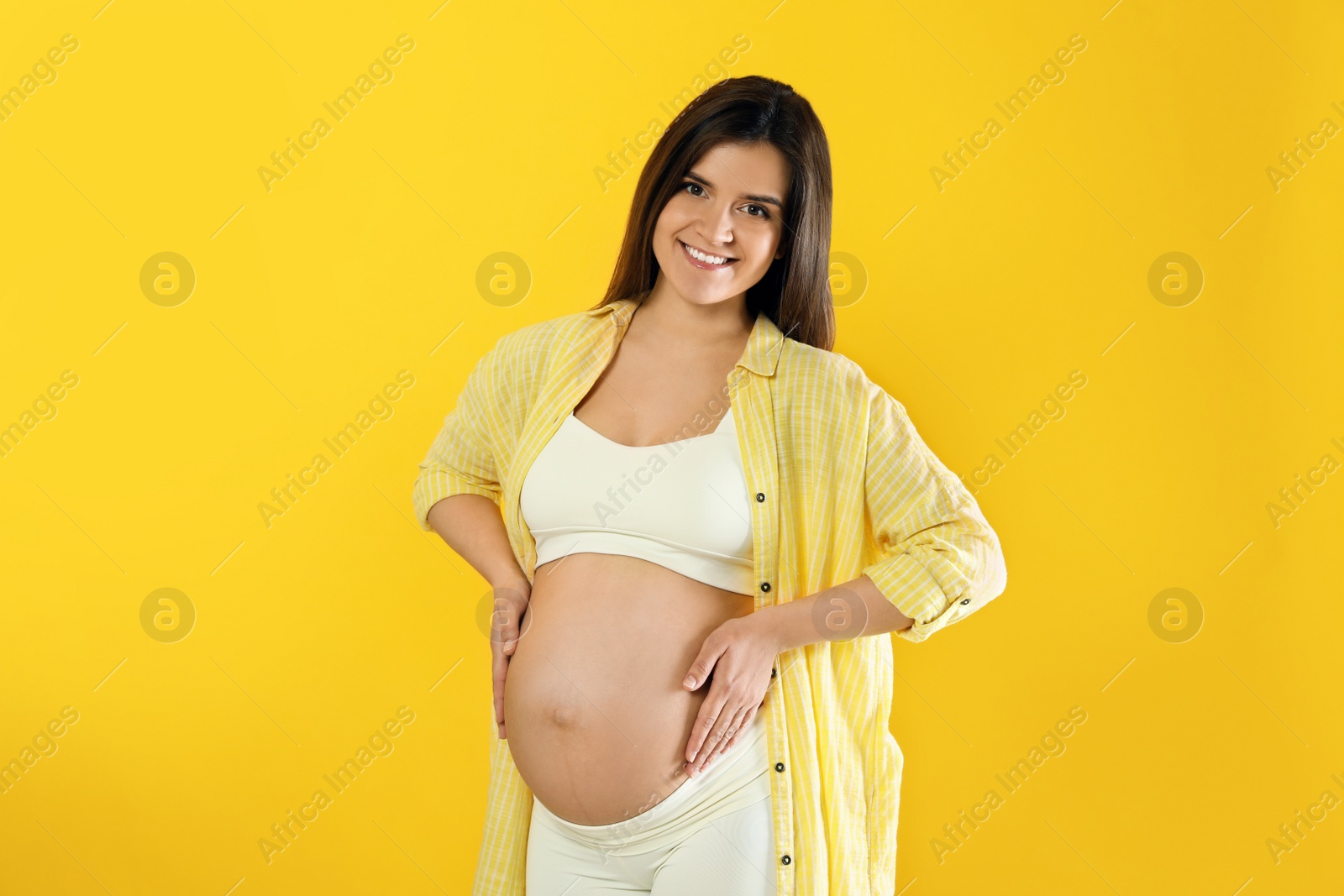 Photo of Happy young pregnant woman on yellow background