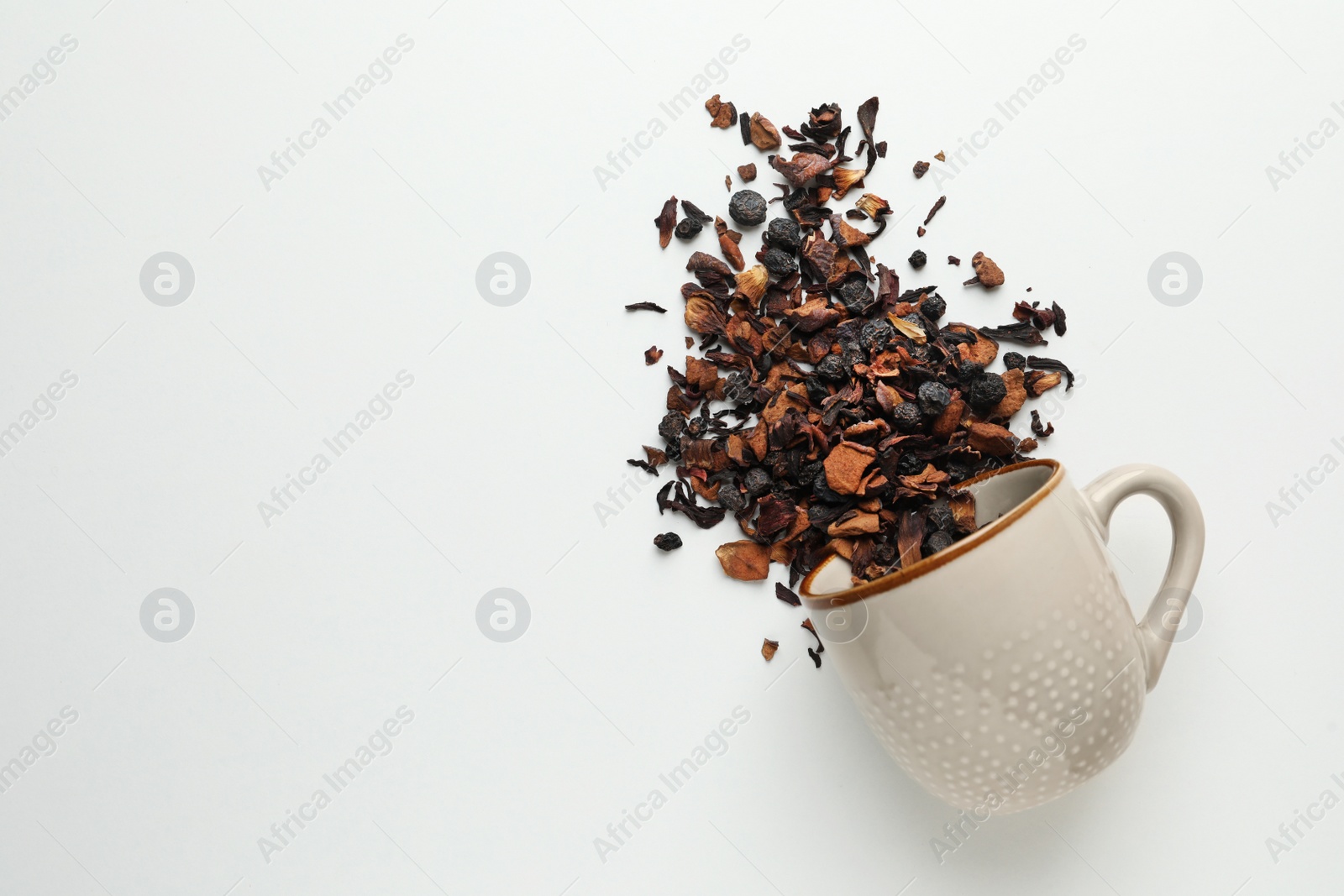 Photo of Cup with scattered dried tea on white background, top view. Space for text