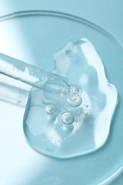 Photo of Pipette with cosmetic serum on light blue background, closeup