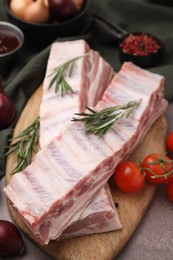Photo of Raw pork ribs, rosemary and tomatoes on table