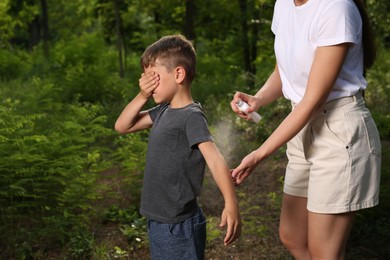 Photo of Woman applying insect repellent on her son's arm in park. Tick bites prevention
