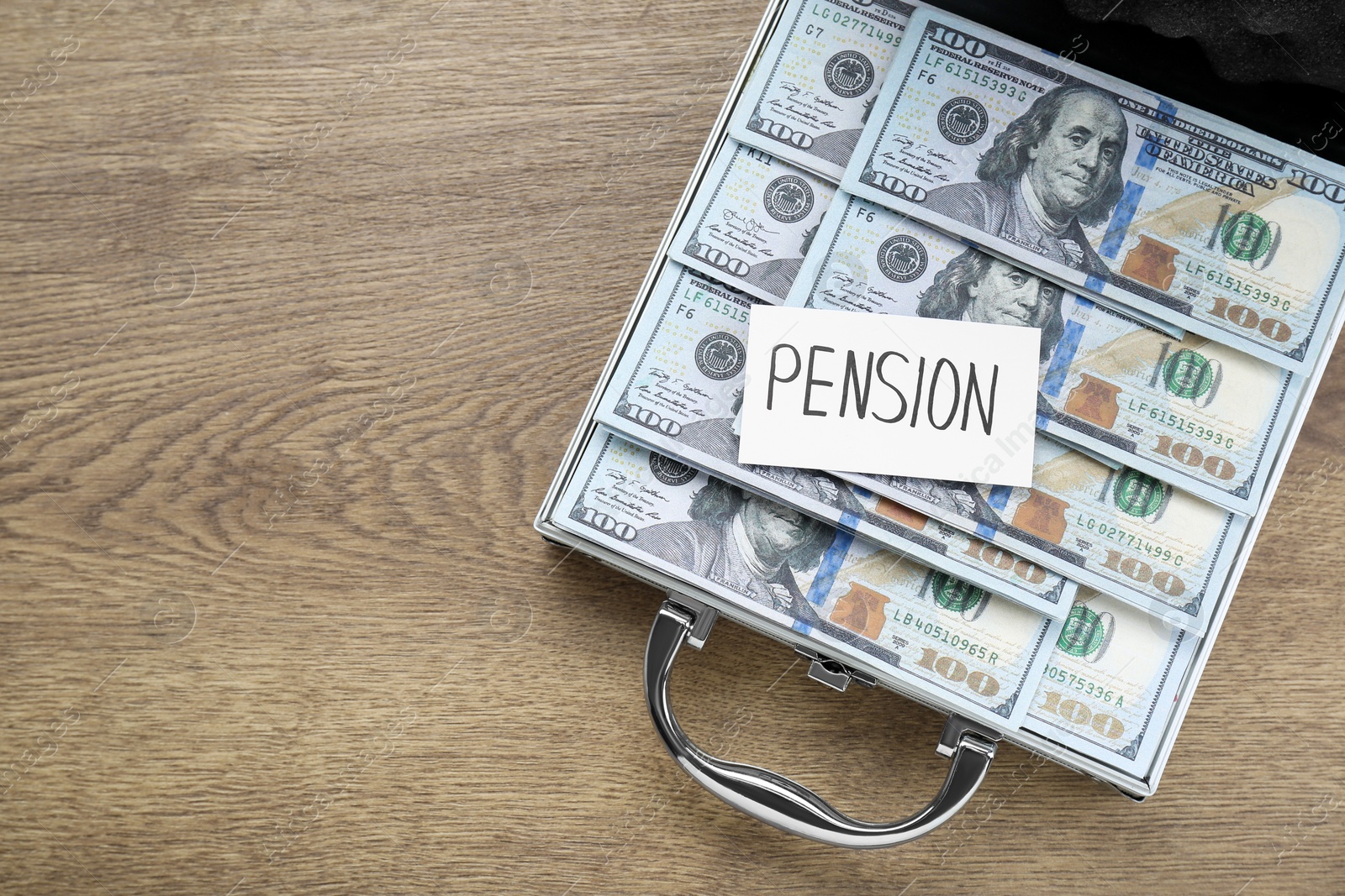 Photo of Card with word Pension and case of dollar banknotes on wooden table, top view. Space for text