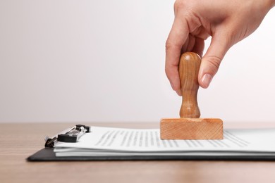 Photo of Woman stamping documents at wooden table, closeup. Space for text