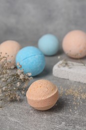 Beautiful aromatic bath bombs and gypsophila flowers on light grey table, space for text