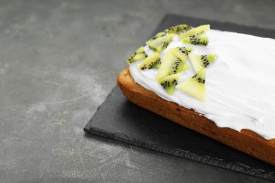 Photo of Delicious homemade yogurt cake with kiwi and cream on gray table, space for text