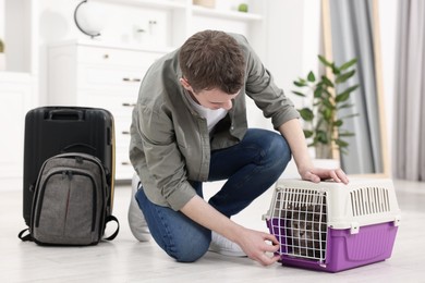 Travel with pet. Man closing carrier with cat at home