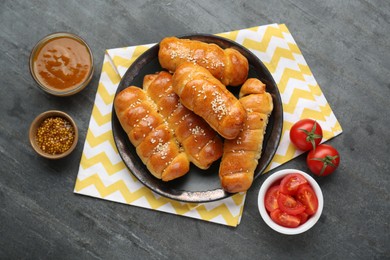 Delicious sausage rolls and ingredients on grey table, flat lay