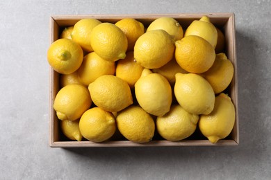 Photo of Fresh lemons in wooden crate on grey table, top view
