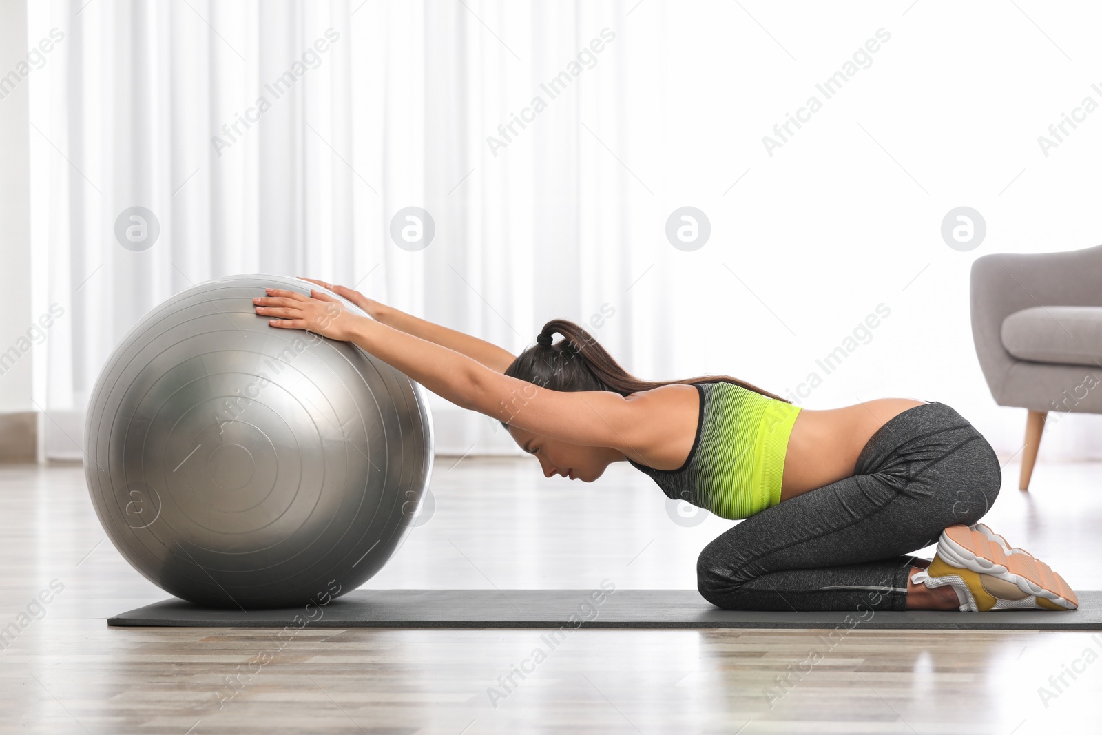 Photo of Young woman doing exercise with fitness ball at home