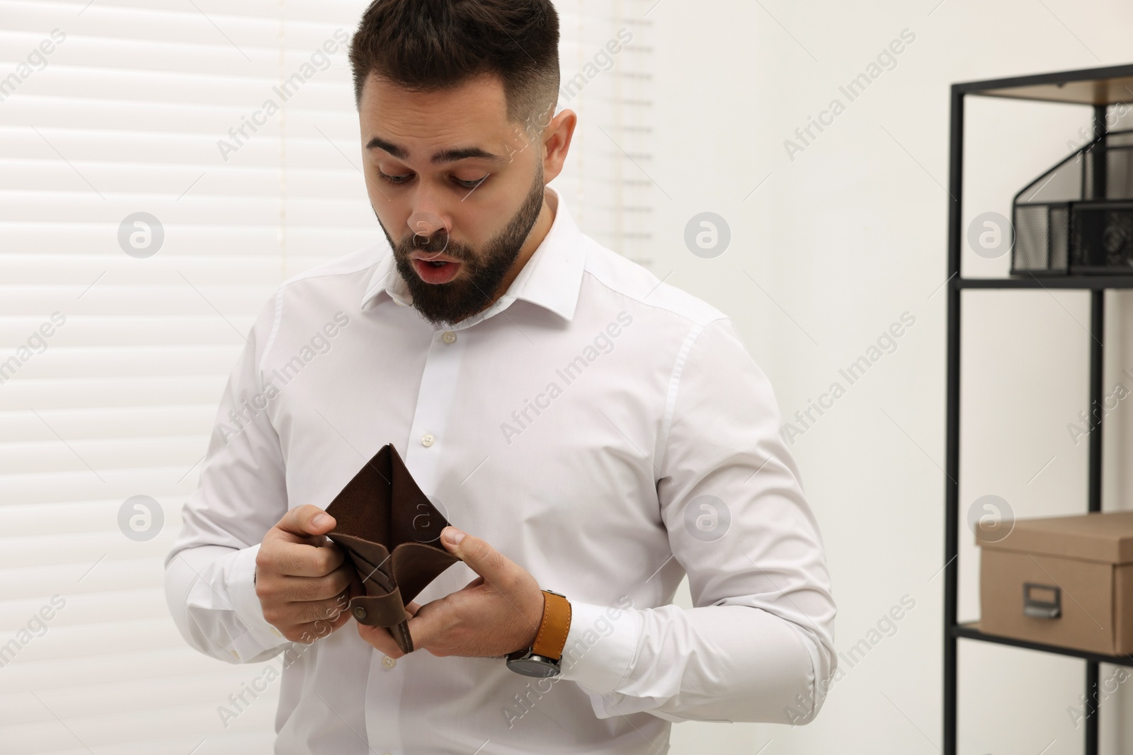 Photo of Confused man with empty wallet in office