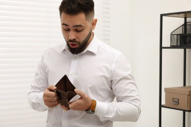 Confused man with empty wallet in office