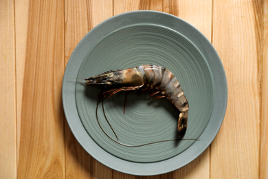 Photo of Fresh black tiger shrimp on wooden table, top view