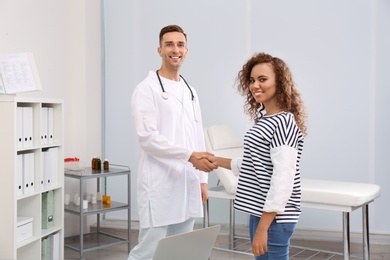 Photo of Doctor and African American patient shaking hands in hospital