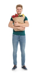 Young man with bag of fresh vegetables on white background