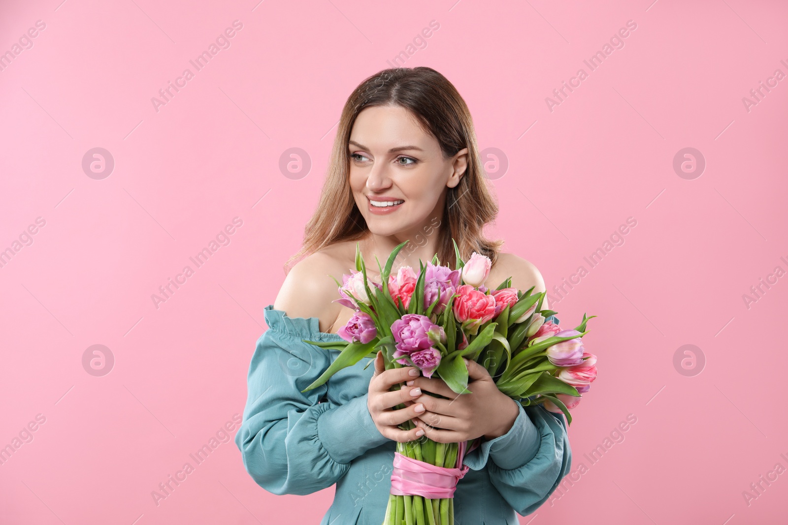 Photo of Happy young woman with bouquet of beautiful tulips on pink background