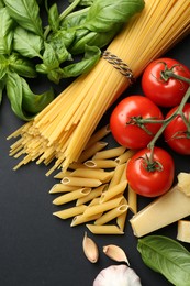 Photo of Different types of pasta, spices and products on black background, flat lay