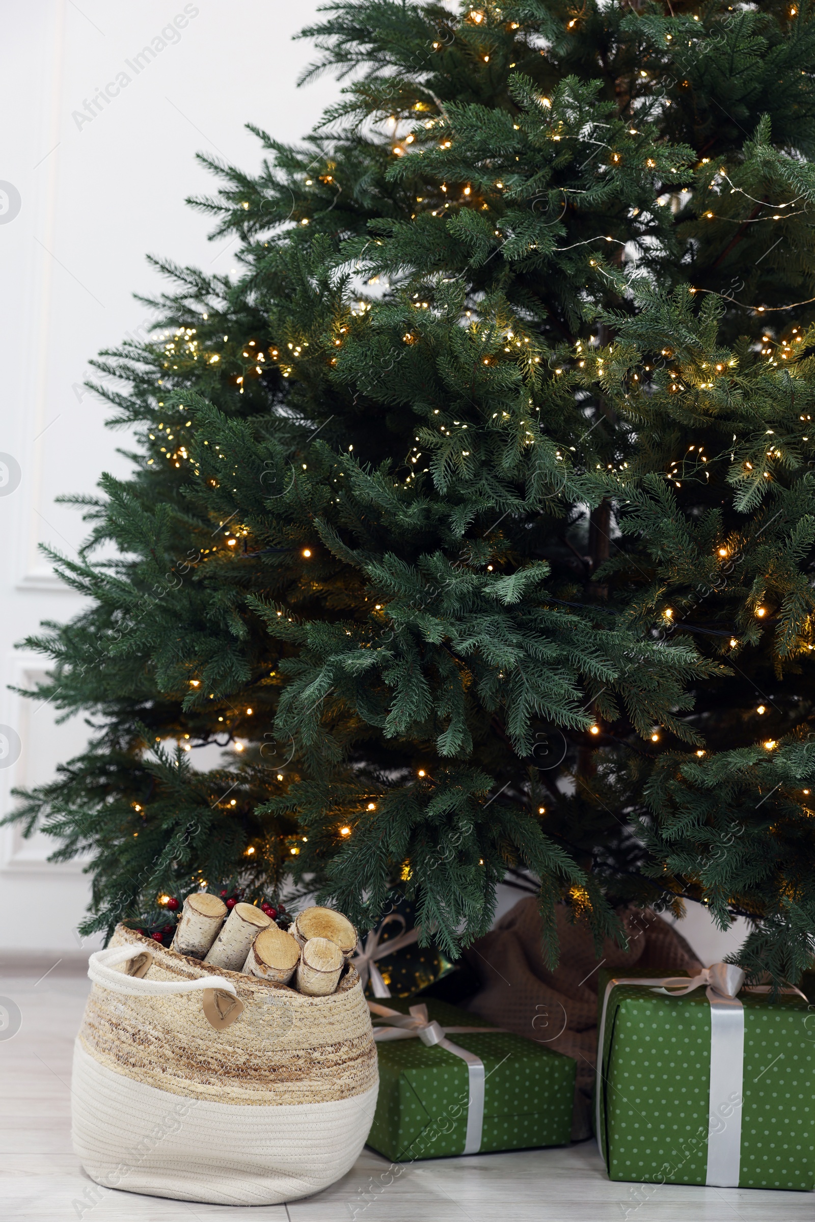 Photo of Many different gift boxes and firewood under Christmas tree indoors