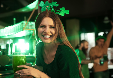 Photo of Young woman with glass of green beer in pub. St. Patrick's Day celebration