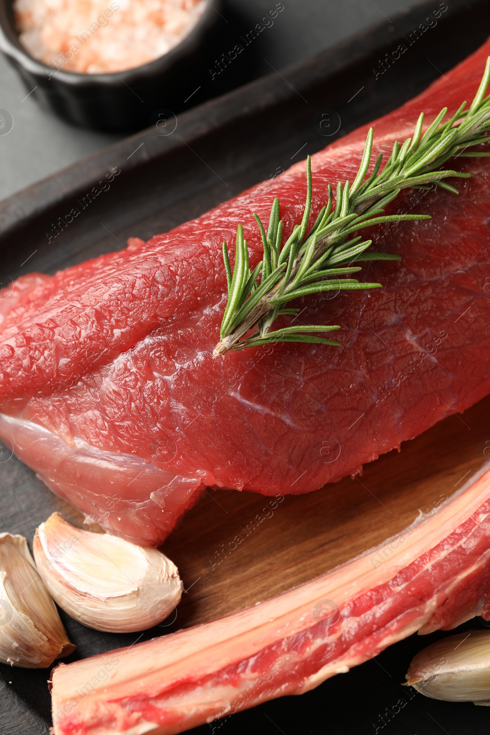 Photo of Pieces of raw beef meat and spices on grey table, closeup