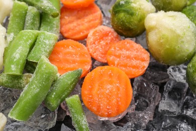 Different frozen vegetables and ice on black table, closeup