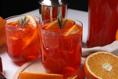 Photo of Aperol spritz cocktail, rosemary and orange slices on white table, closeup