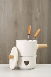 Fondue set on white wooden table. Kitchen equipment