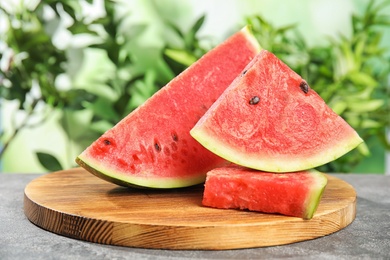 Photo of Wooden board with juicy watermelon slices on table