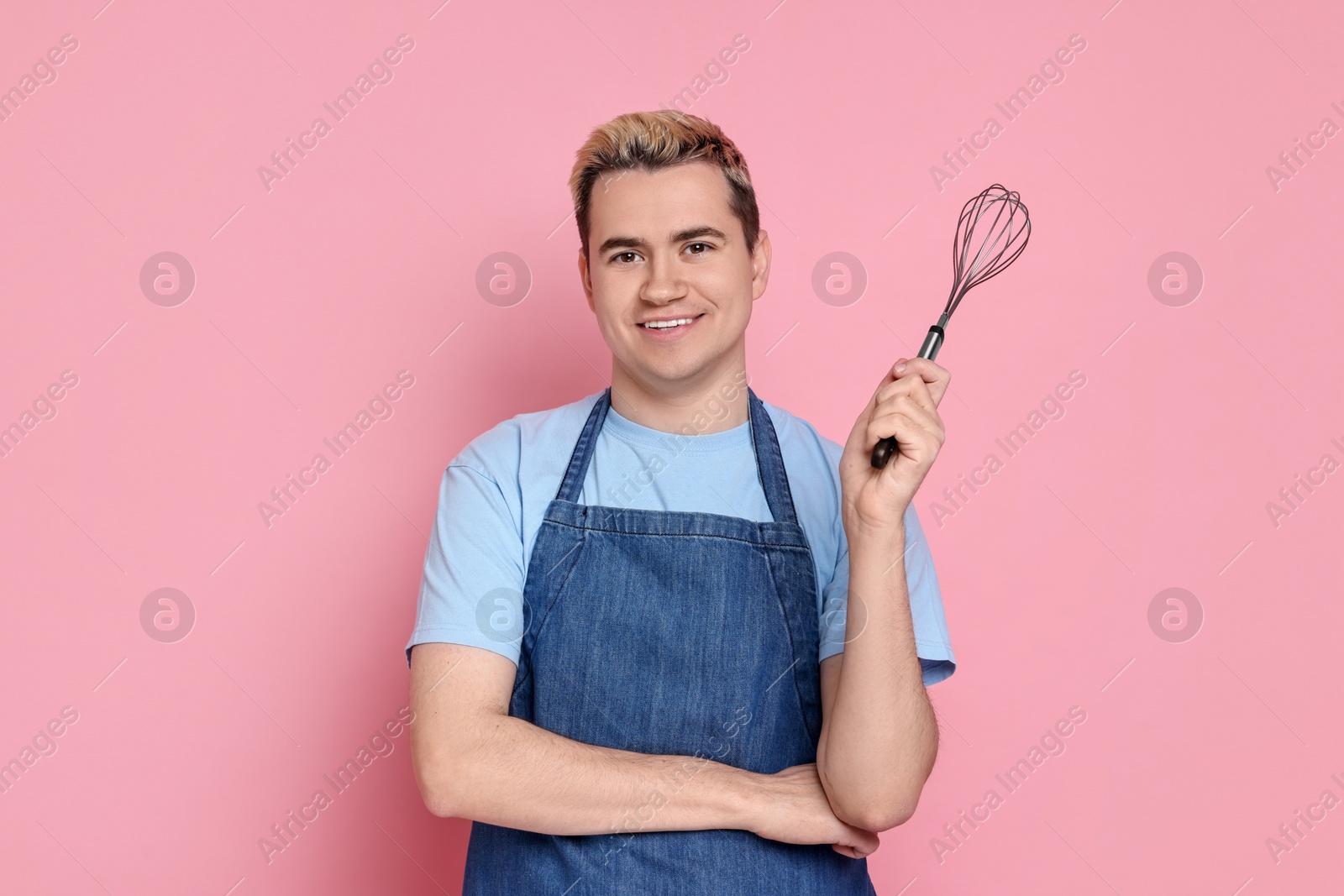 Photo of Portrait of happy confectioner holding whisk on pink background