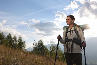 Photo of Tourist with backpack and trekking poles hiking through mountains, space for text