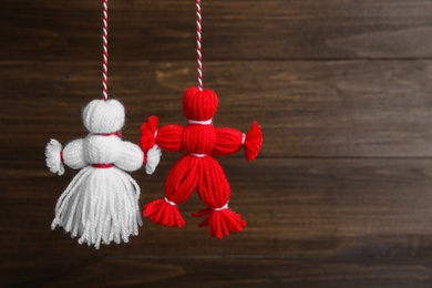 Photo of Traditional martisor shaped as man and woman on wooden background, space for text. Beginning of spring celebration