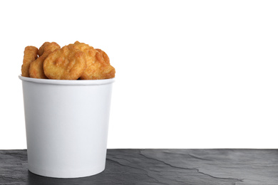 Photo of Bucket with tasty chicken nuggets on black table against white background. Space for text