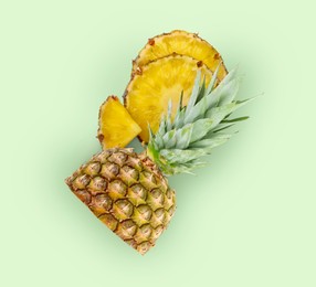 Image of Cut fresh juicy pineapple on pale green background, top view