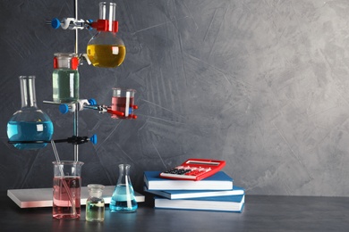 Photo of Laboratory glassware and school supplies on table against grey background, space for text