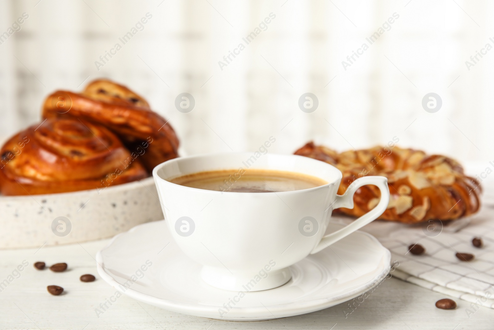 Photo of Cup of coffee and fresh tasty pastries on white wooden table