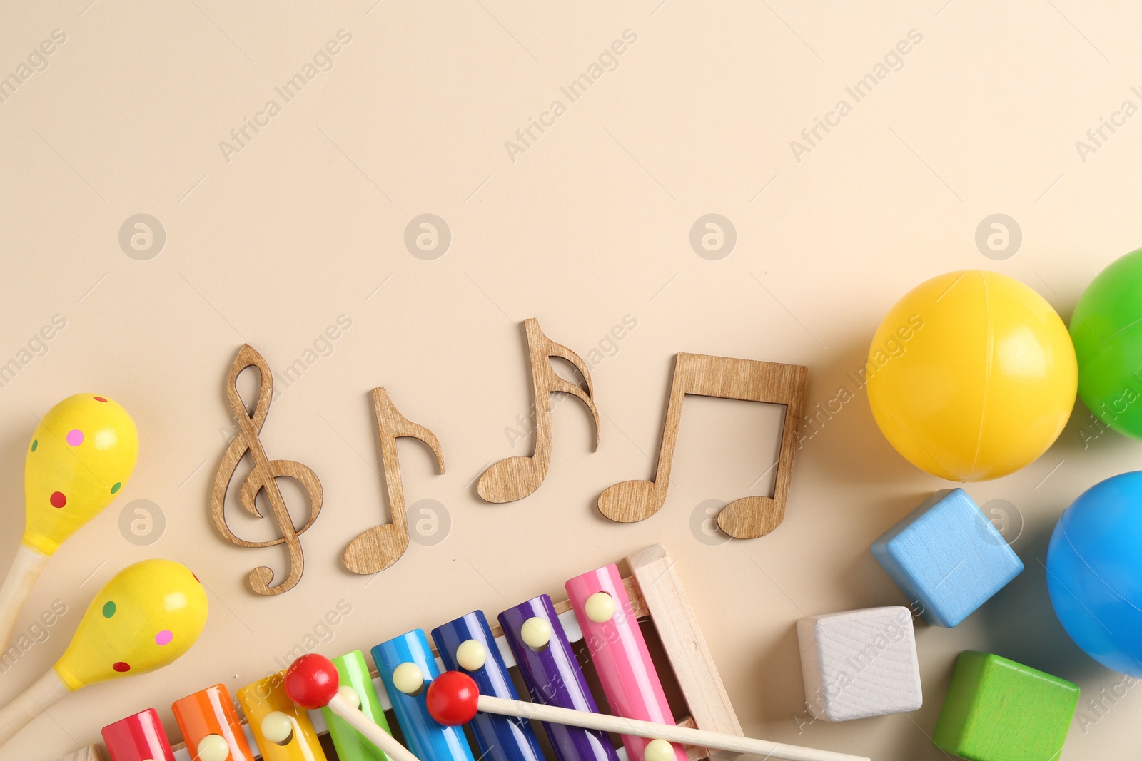 Photo of Baby song concept. Wooden notes, kids xylophone and toys on beige background, flat lay. Space for text