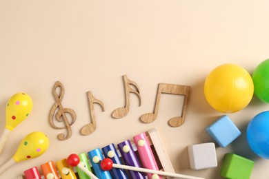 Baby song concept. Wooden notes, kids xylophone and toys on beige background, flat lay. Space for text