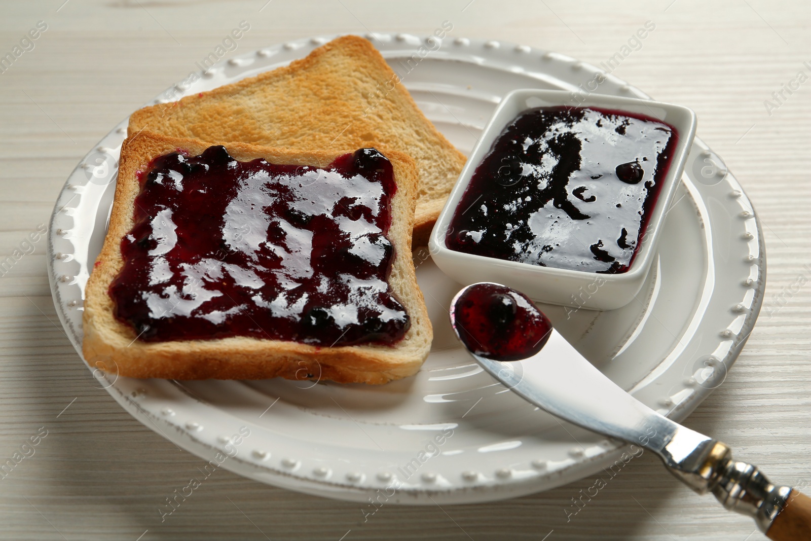 Photo of Delicious toasts with jam served on white wooden table, closeup