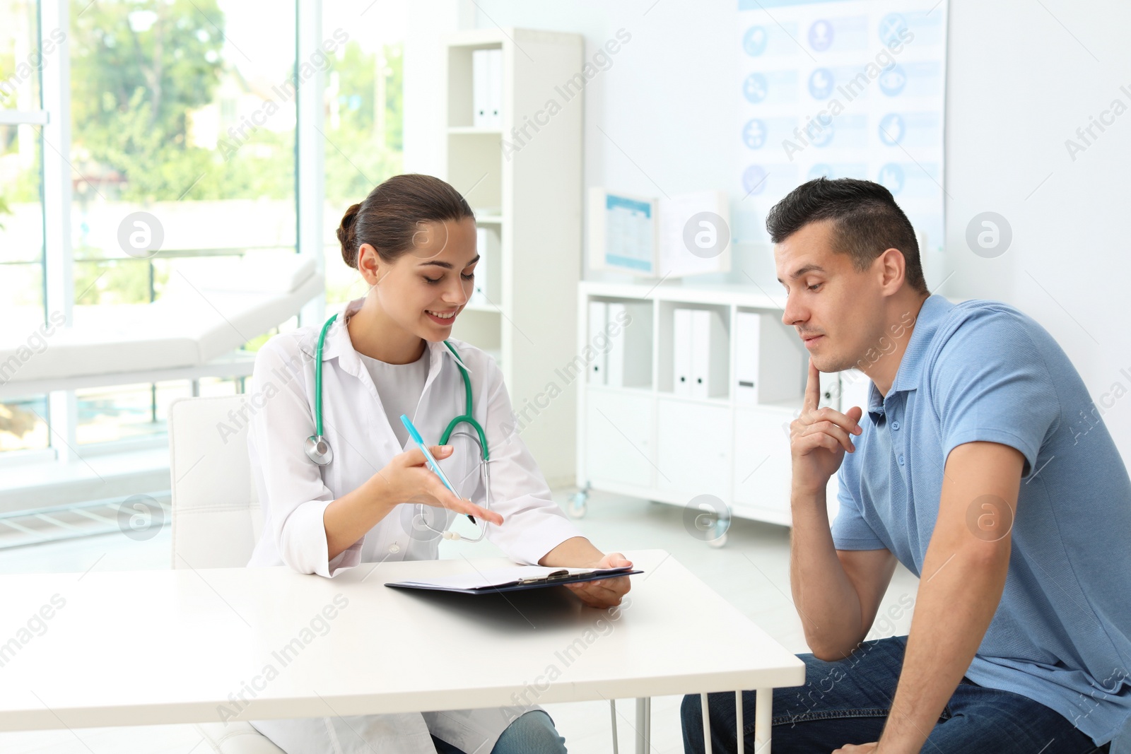 Photo of Young doctor speaking to patient in hospital