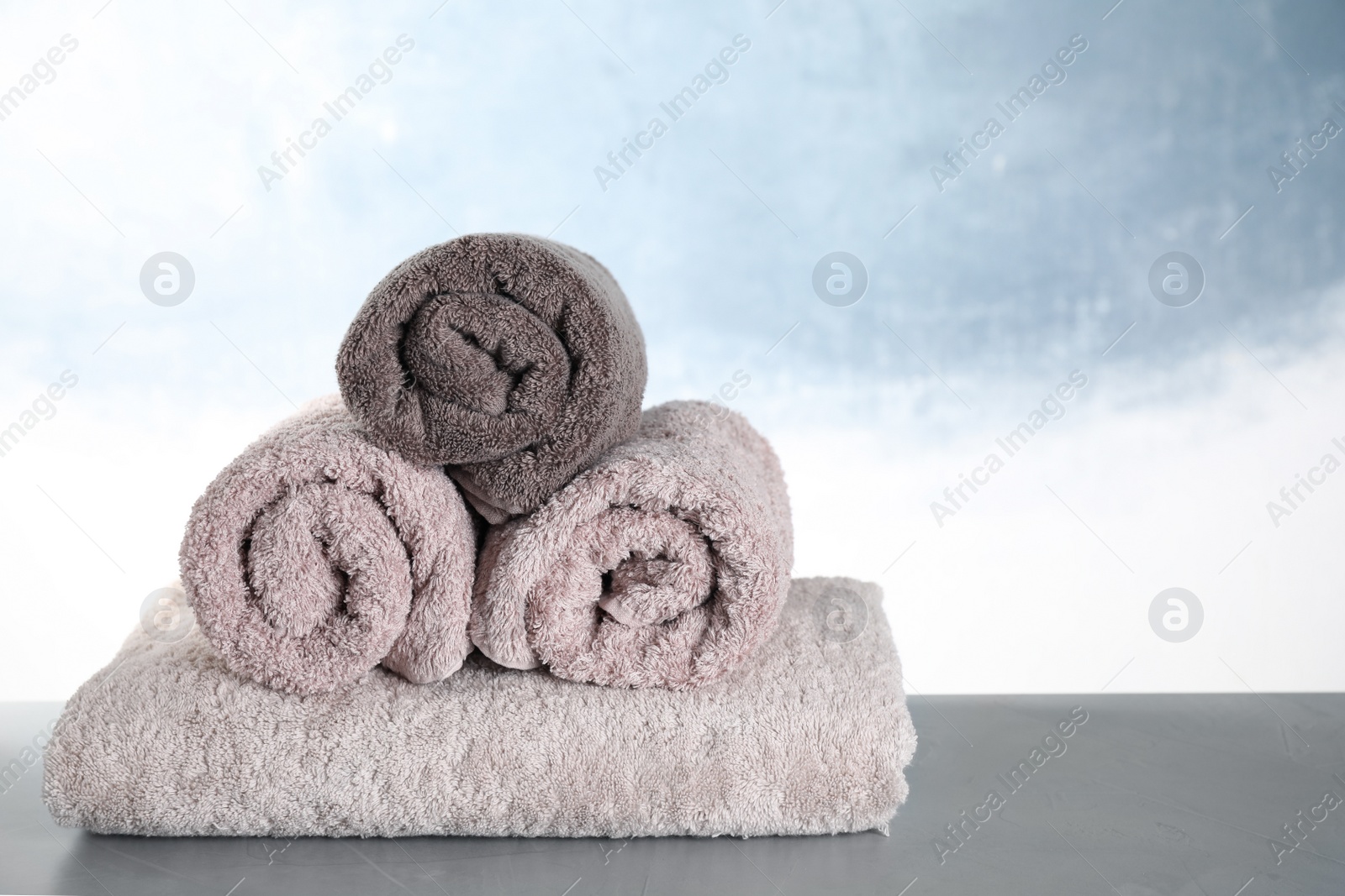 Photo of Fresh folded bath towels on grey table. Space for text