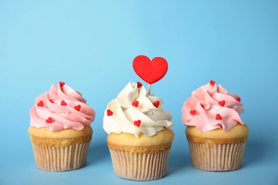 Photo of Tasty cupcakes for Valentine's Day on light blue background