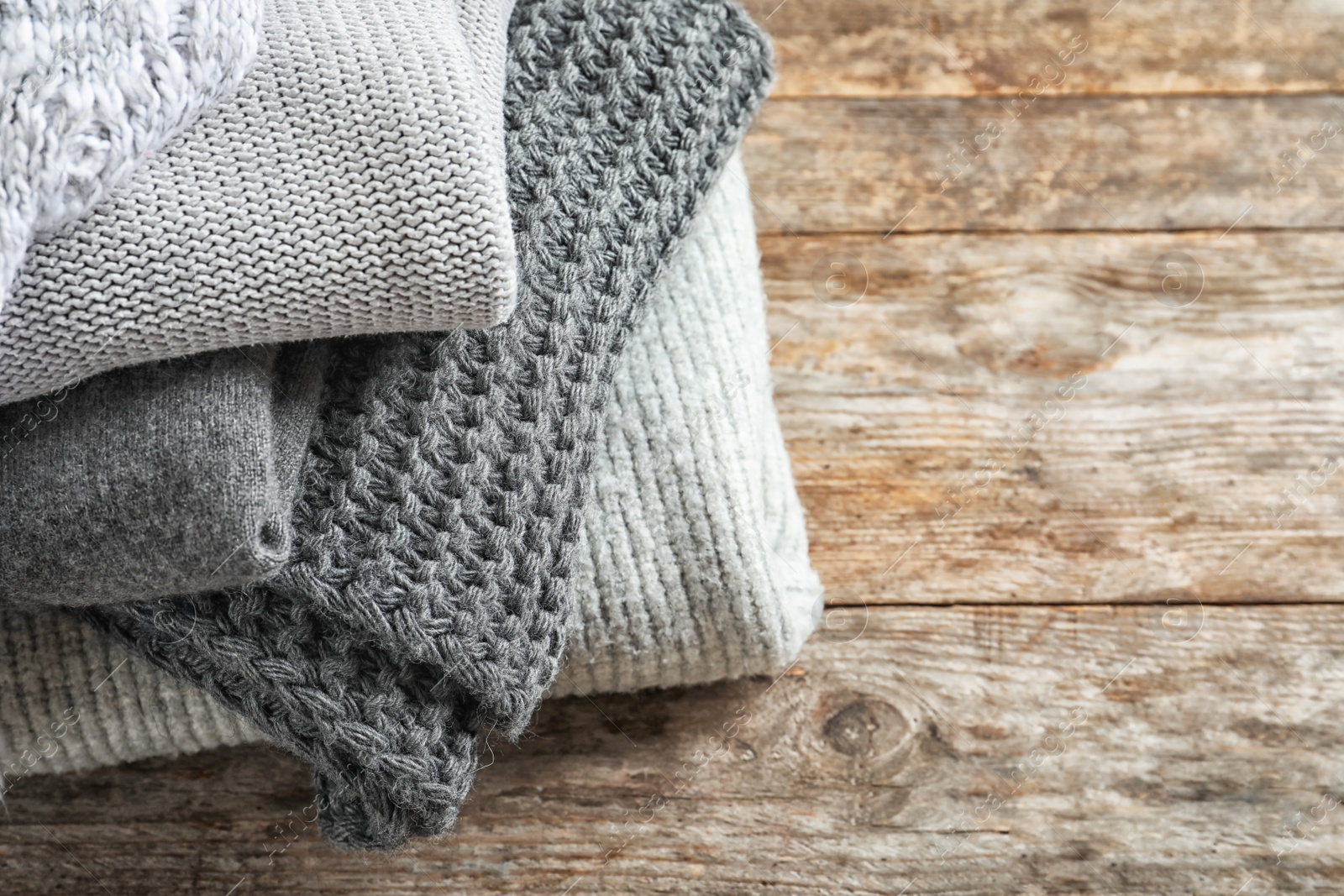 Photo of Pile of warm knitted clothes on table