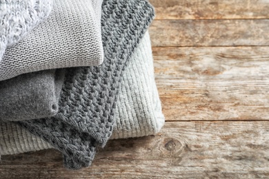 Photo of Pile of warm knitted clothes on table