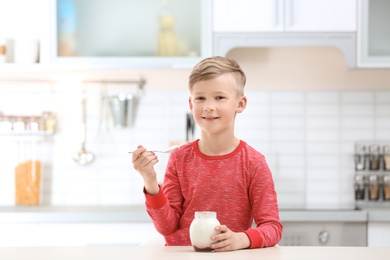 Photo of Little boy with yogurt in kitchen