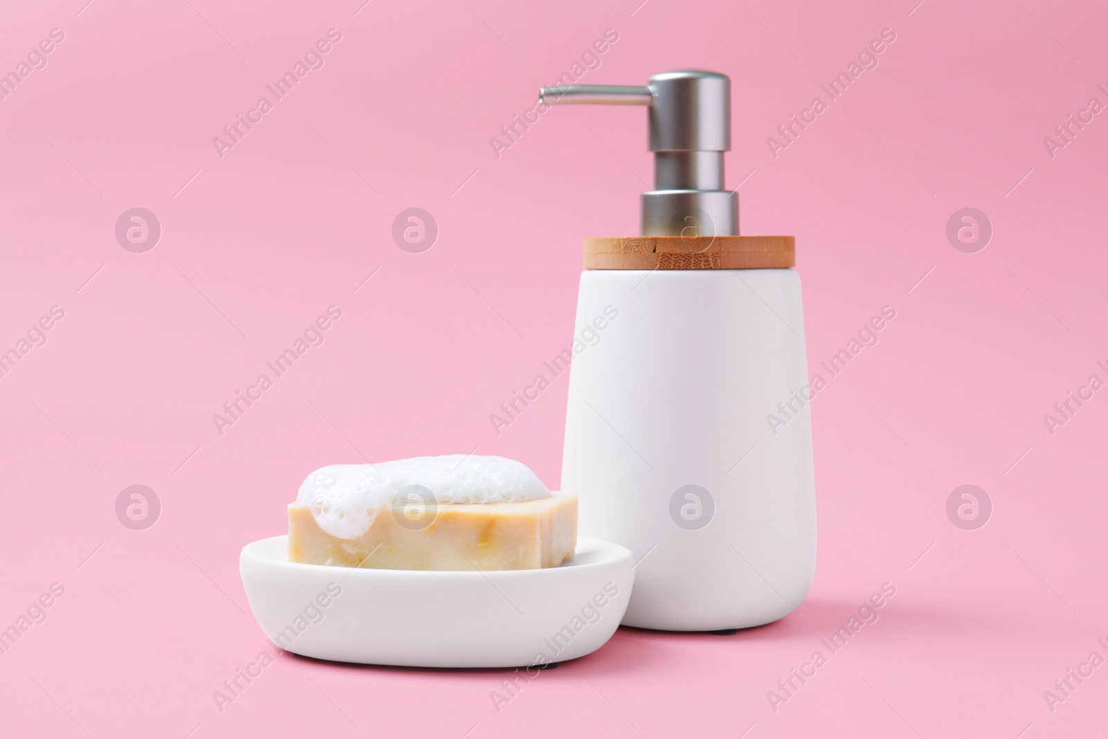 Photo of Soap bar and bottle dispenser on pink background