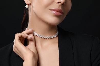 Photo of Young woman with elegant pearl jewelry on black background, closeup